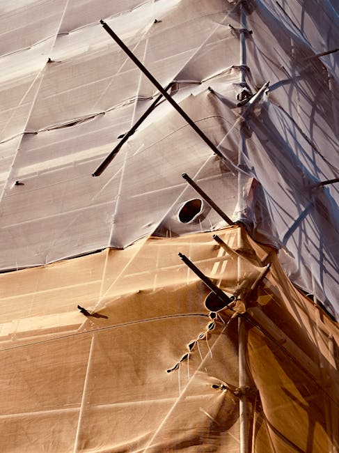 Abstract view of a construction scaffold with sunlit fabric tarpaulin covering, highlighting the geometric lines.