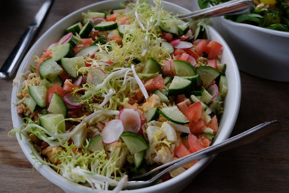 Delicious and healthy organic vegetable salad with radishes, cucumbers, and frisée in a white bowl.