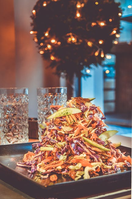 Vibrant vegetable salad with Christmas lights and glasses, perfect for a festive meal.