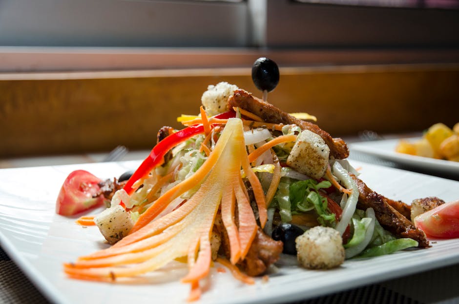 Appetizing healthy salad with fresh vegetables and fried chicken decorated with black olives and served in white plate
