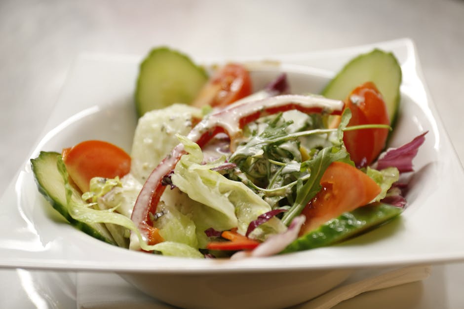 Close-up of a vibrant vegetable salad with creamy dressing, showcasing fresh ingredients like cucumber and tomato.