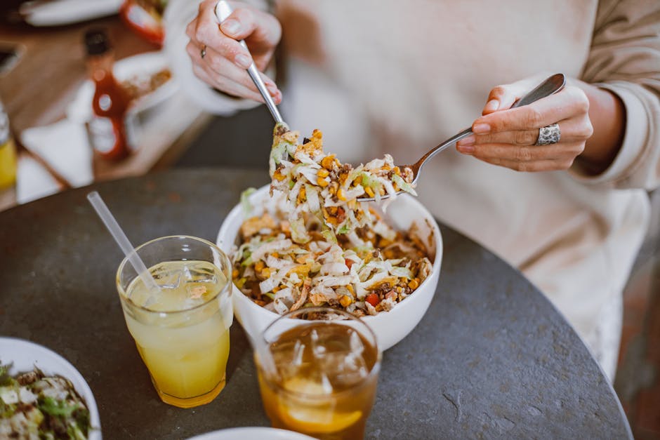 Close-up of a person enjoying a nutritious salad with refreshing drinks, perfect for a healthy lunch.