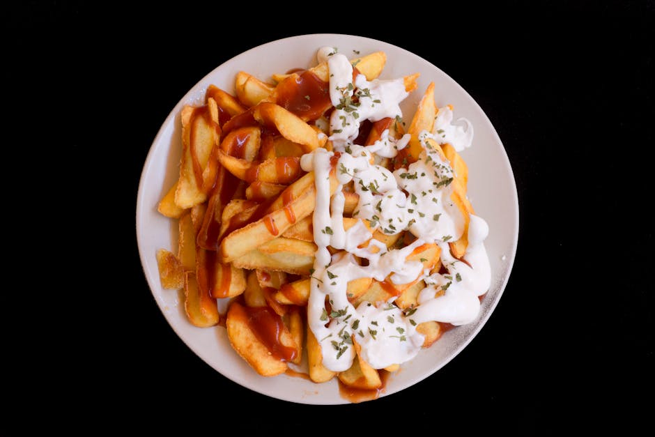 A plate of crispy fries topped with creamy sauce and herbs, perfect as a delicious snack.