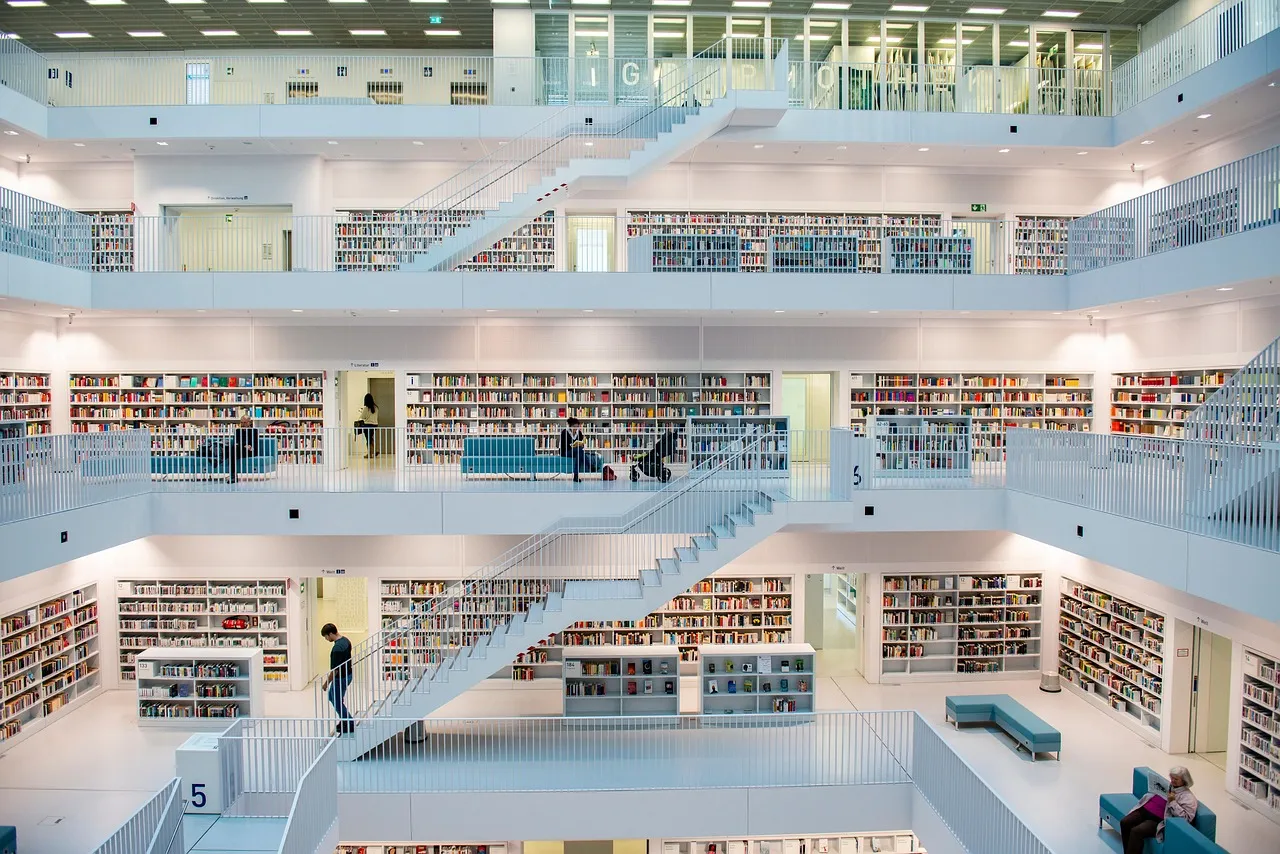 Een modern, wit interieur van een bibliotheek met meerdere verdiepingen en veel boeken.