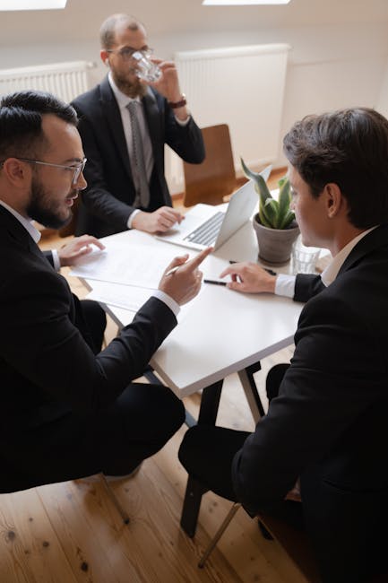 Three businessmen engaged in discussion during a formal meeting in an office setting.