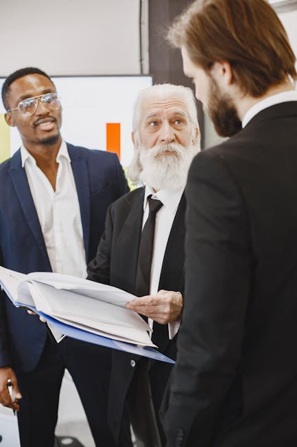 A diverse group of businessmen engaged in a meeting, discussing reports in an office setting.