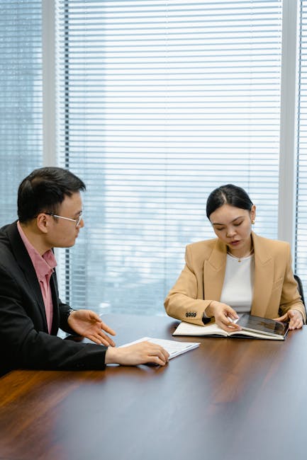 Two business professionals discussing documents in a modern office.