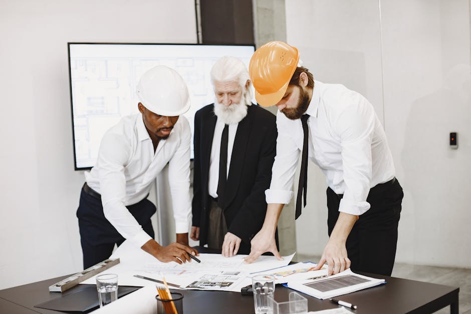 Three professionals in an office setting reviewing building plans and collaborating on a construction project.