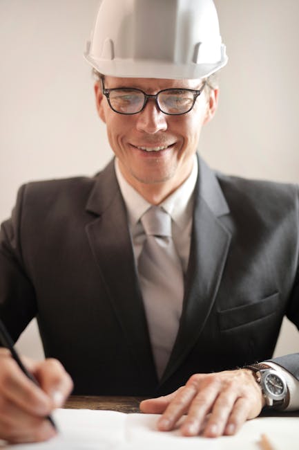 Male engineer in formal attire reviewing and signing construction documents indoors.