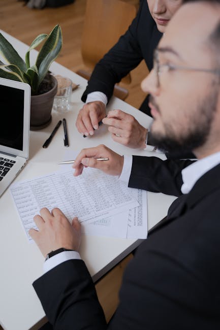 Businessmen in suits reviewing paperwork during a meeting at the office.