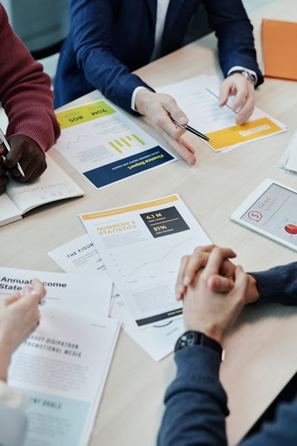 Team members discuss data reports and statistics in a collaborative setting around a table.