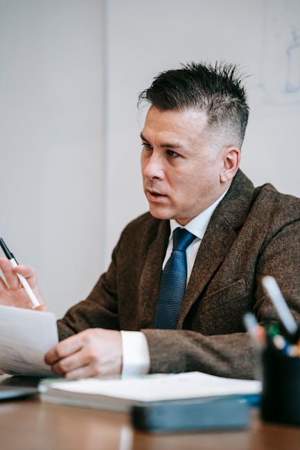 Focused businessman in formal attire analyzing documents at a desk.