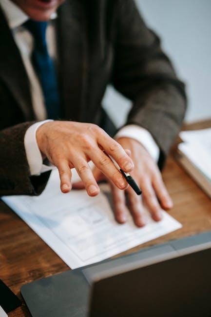 A business professional in formal attire reviewing documents with a pen in hand, showcasing professional focus.