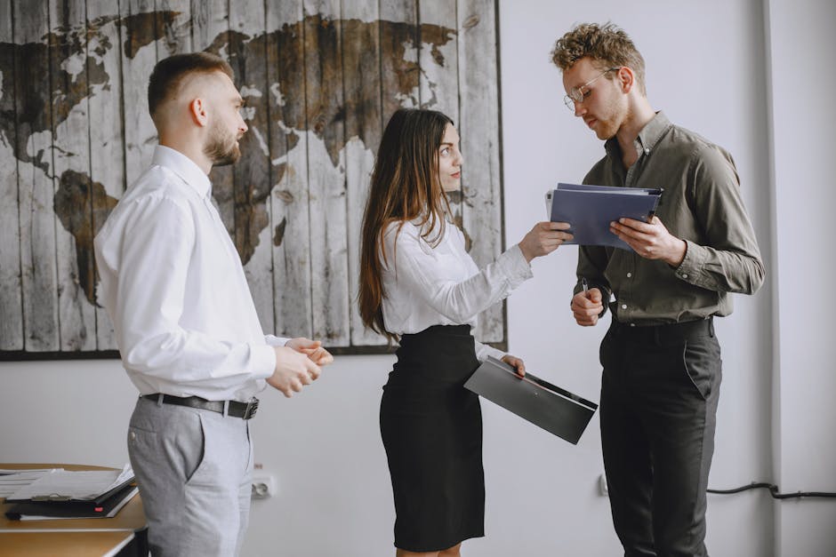Three young professionals discussing documents in a modern office space.