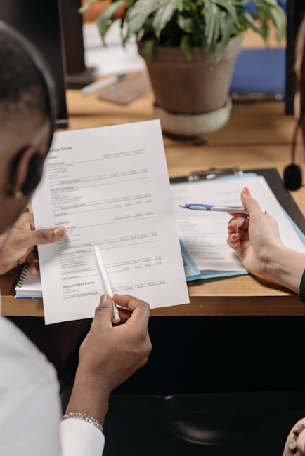 Two professionals reviewing financial documents and discussing strategy in an office environment.
