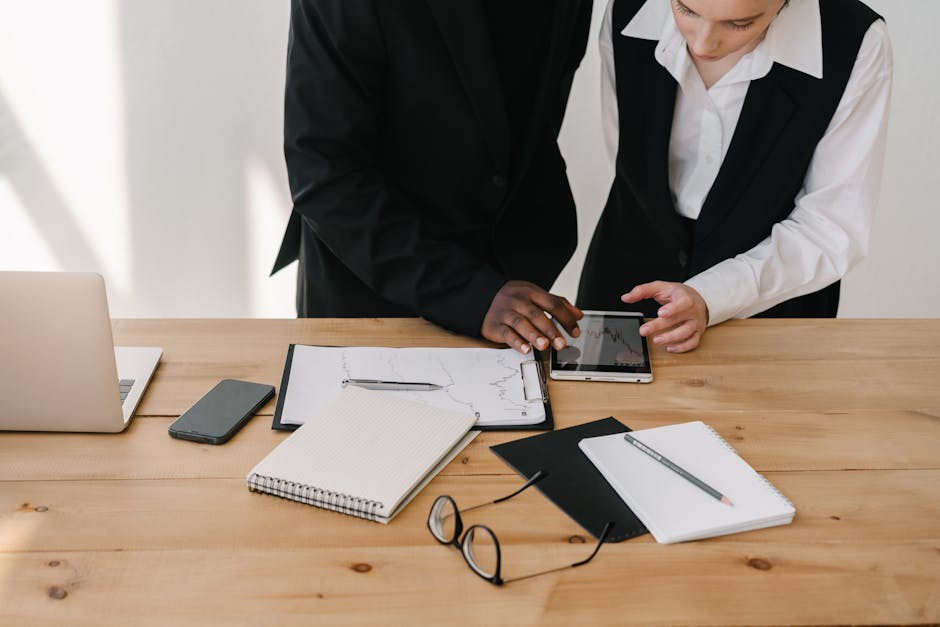 Two professionals collaborating over charts and tablet in a modern office setting.