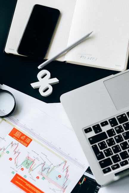 A stylish office setup featuring financial charts, laptop, and smartphone for data analysis.