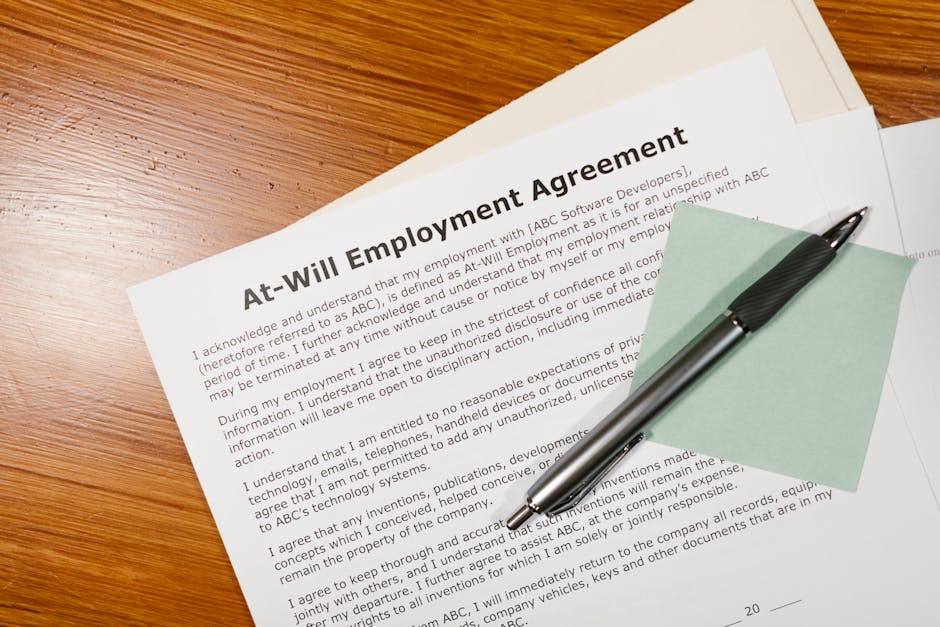 Close-up of an at-will employment agreement on a wooden desk with a pen, emphasizing legal and business concepts.