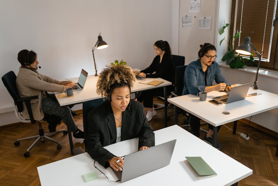 Diverse team of call center agents working at computers in an office setting, focused on tasks.