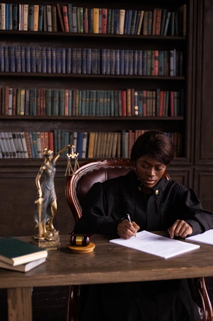 Black female judge sitting at desk in library, writing legal documents.