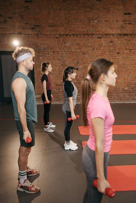 A diverse group of adults working out with dumbbells in an industrial-style gym.