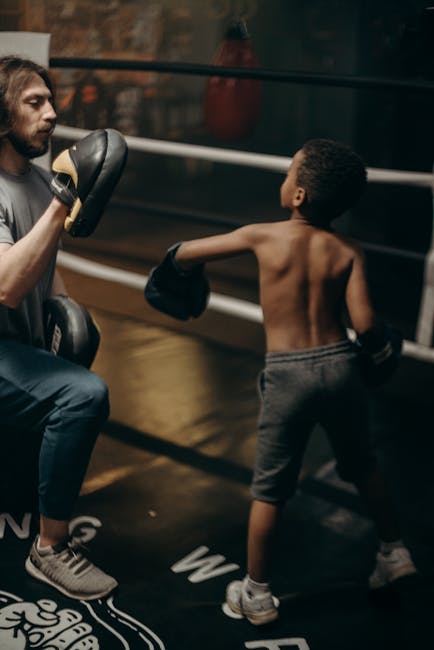 Young boy practicing boxing with coach in a gym, focusing on technique and fitness.