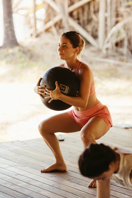 A woman performing a squat exercise with a medicine ball in an outdoor fitness setting, showcasing strength and balance.