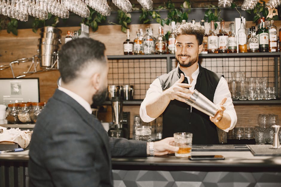 Bartender skillfully shaking cocktail with a smiling interaction at a stylish bar.