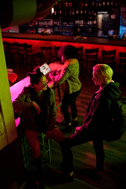 A lively bar scene with friends enjoying their night out, highlighted by colorful lighting.