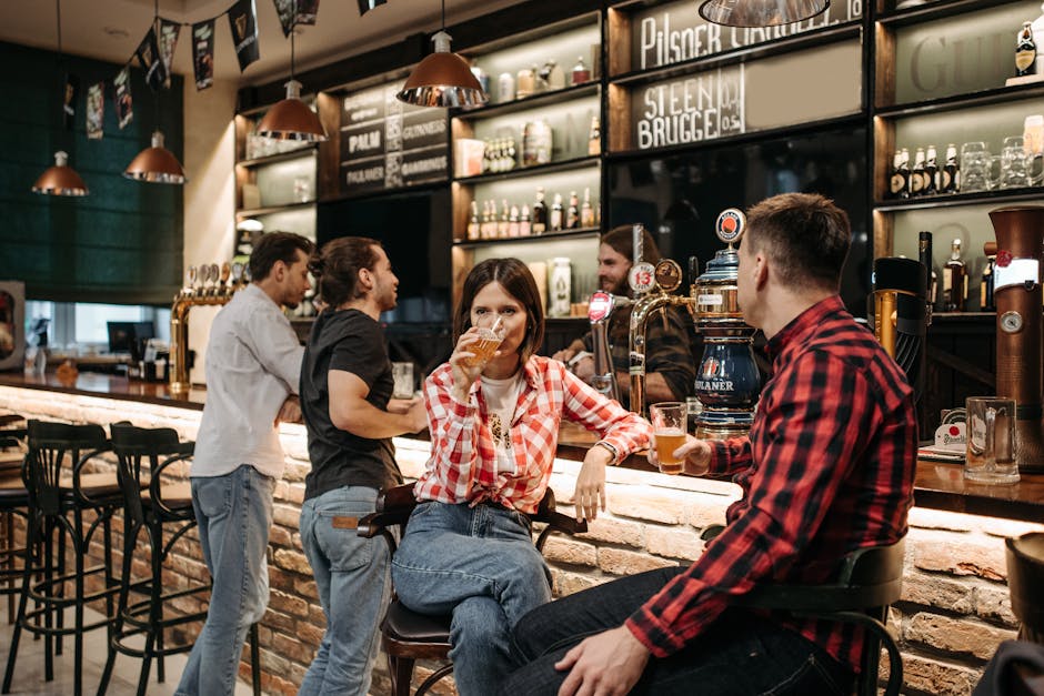 Casual group of friends drinking beer and socializing at a lively bar counter indoors.