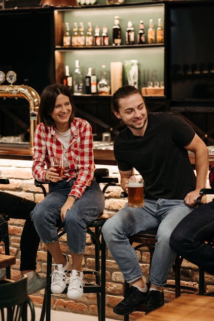 Two friends enjoying drinks at a pub, smiling and bonding over a beer.