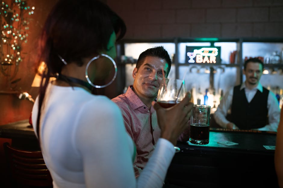 Two adults enjoying drinks at a lively bar with colorful lighting.
