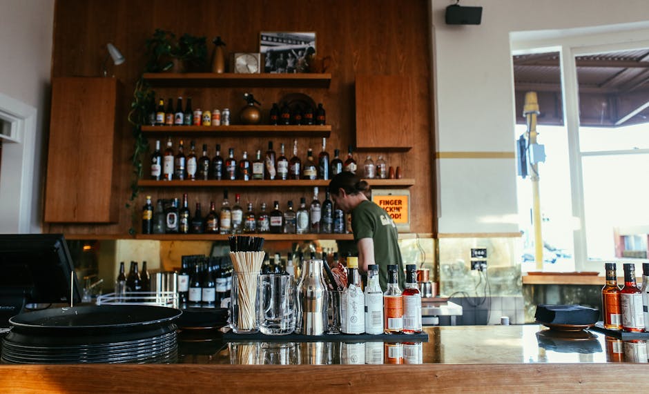 A bartender working behind a well-stocked bar with various bottles and drinks.