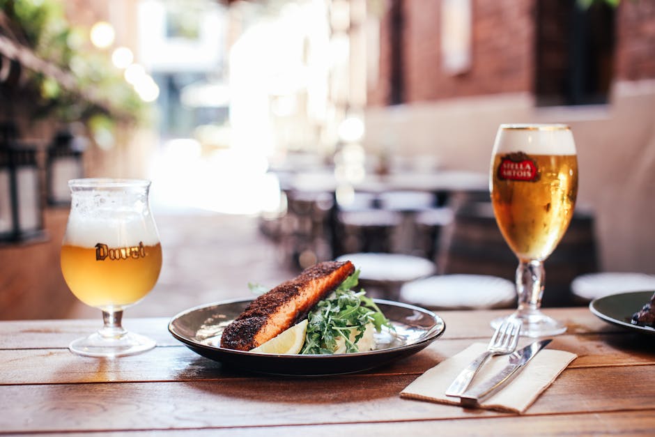 An outdoor dining setup featuring beer and a grilled meal on a rustic table.