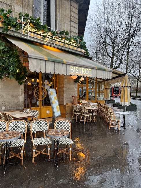 Outdoor seating of a Paris bistro on a rainy day with empty wicker chairs.