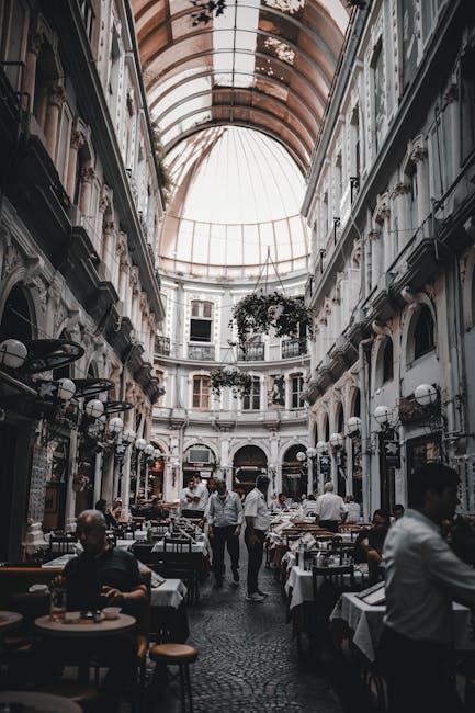 A bustling indoor arcade with a classic dome and dining tables, creating a tranquil ambiance.