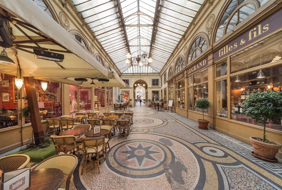 Discover the charm of Paris in a classic passage with ornate architecture, inviting café tables, and vintage shops.