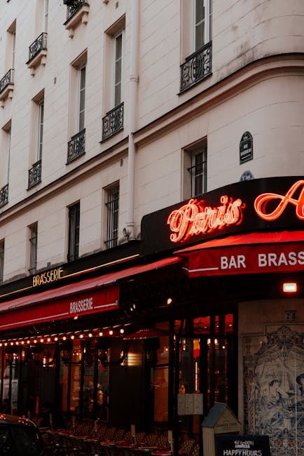 View of a Parisian brasserie with vibrant neon signs and classic architecture.