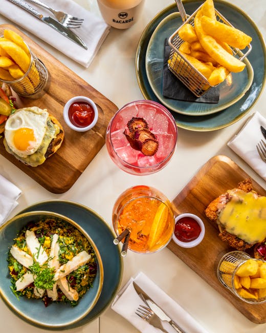 Top view of a delicious brunch spread featuring meats, fries, and refreshing drinks in a restaurant.