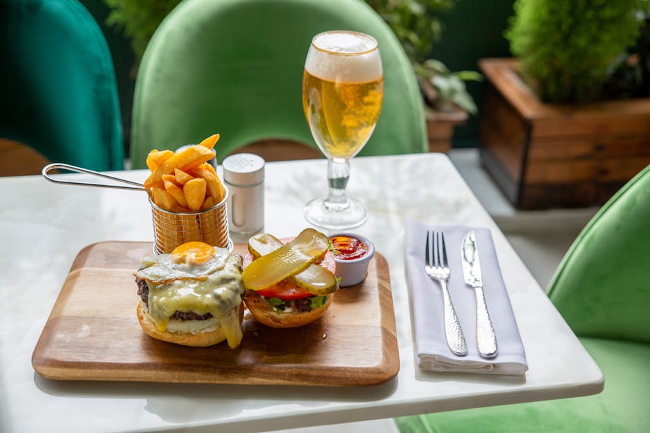 Mouth-watering burger with fries and beer on a stylish table, perfect for food photography.