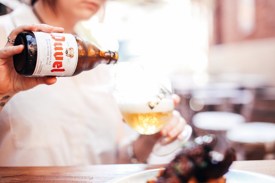 Close-up of woman pouring beer into a glass at a bar setting.