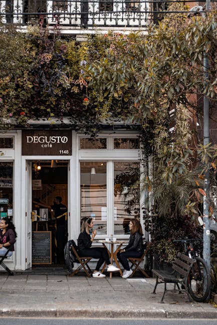 Two women enjoying coffee at Degusto Café in Curitiba, amid lush greenery.