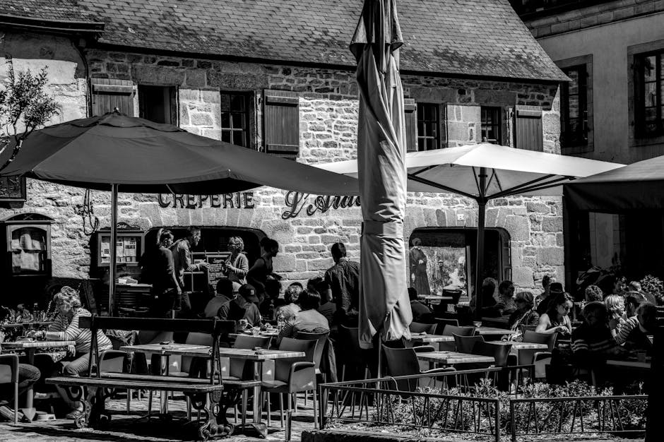 Black and white photo of people dining in a Breton café's terrace.