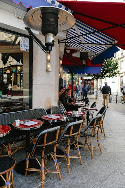 Charming Parisian café setting with outdoor seating and vibrant red awnings, capturing city life.