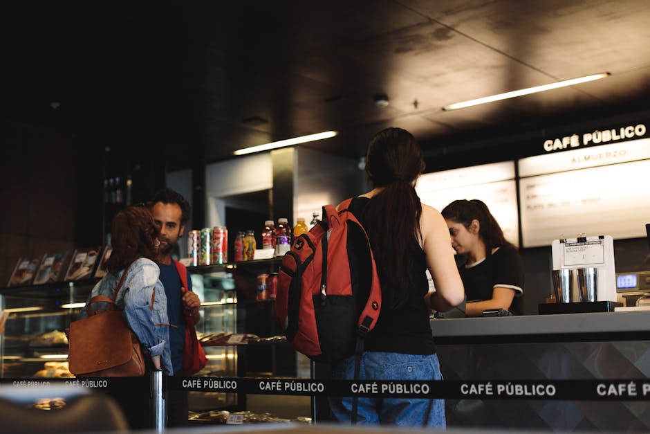 Young adults interacting at a modern café counter, ordering and conversing.