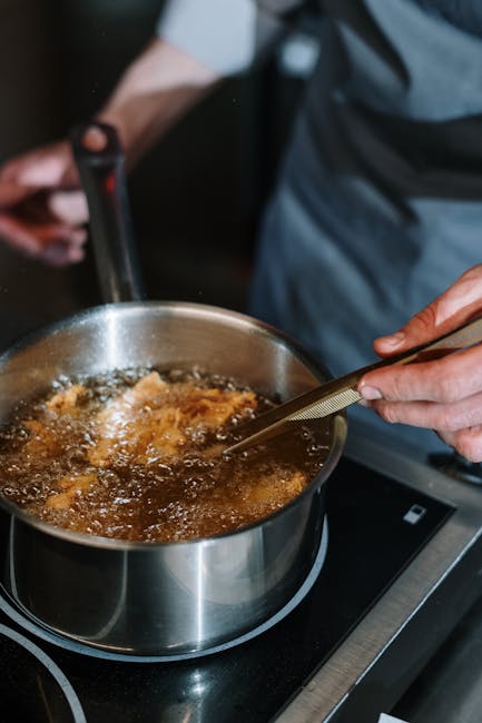 A close-up of a chef frying food in a saucepan on a stove, showing culinary expertise.