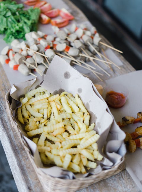 Close-up of crinkle-cut fries in a basket with an assortment of grilled skewers.
