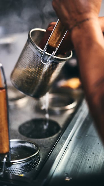 Close-up of a chef boiling pasta in a kitchen with steaming water.