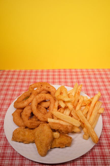 Crispy onion rings, French fries, and nuggets served on a vibrant red plaid tablecloth.