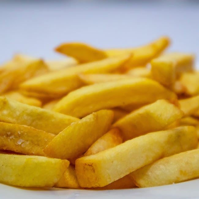 A mouthwatering close-up of crispy golden french fries on a plate.